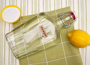 bottle of vinegar and a lemon resting on a dishtowel