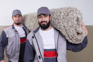 carpet installers hauling in a roll of carpet