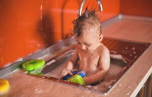 Cute Baby Boy taking a bath in Kitchen Sink